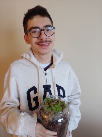 Student holding a plant in a mason jar